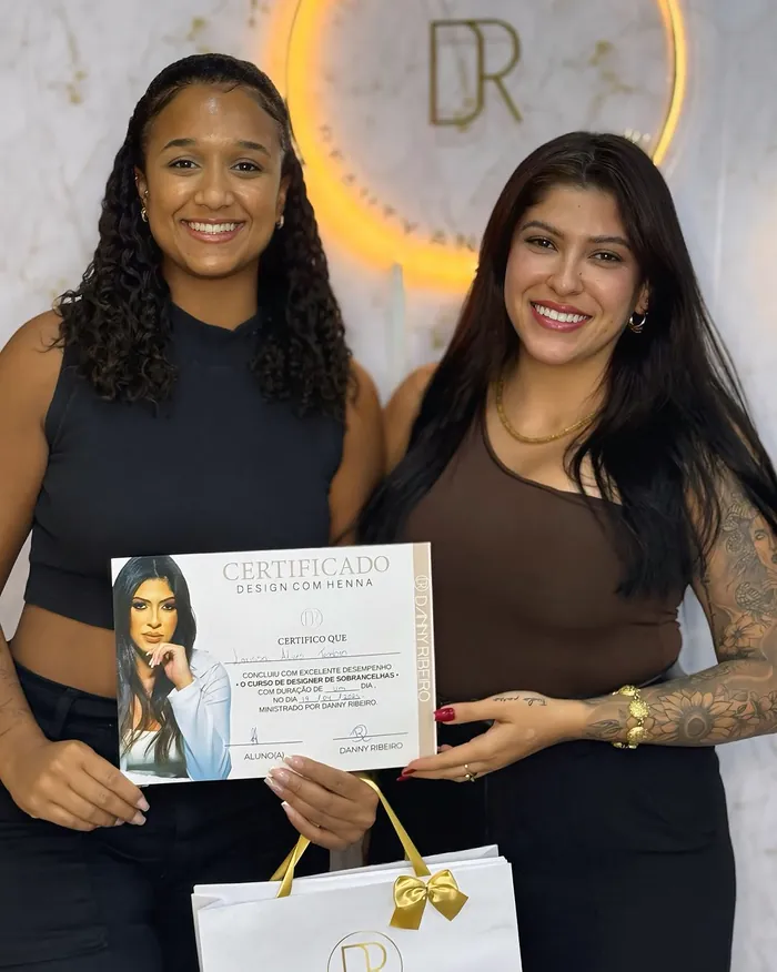 Aluna formada com certificado diante do letreiro do studio